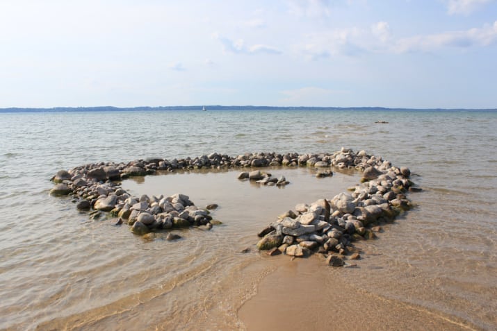 What it means everywhere else: A mass of sand accompanying an ocean.What it means in the Midwest: Sand around a lake. Or rocks. We aren\'t very picky.